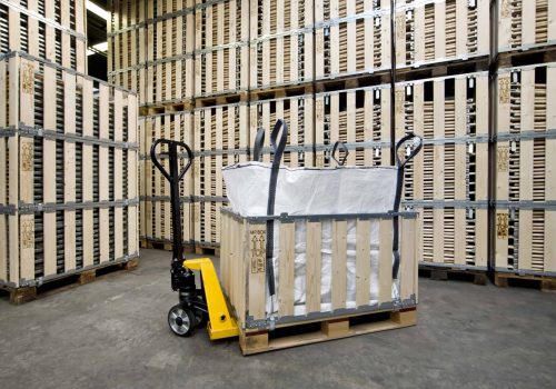 Afbeelding van een palletwagen met verpakte materialen in een magazijn.